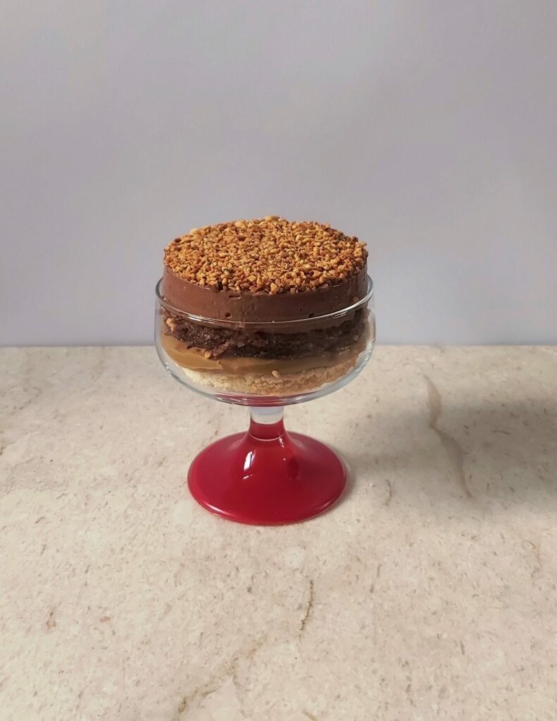 Dolce al bicchiere a strati. Dall'alto: nocciole caramellate, mousse al cioccolato, massa montata al cacao inzuppata al rum, cremoso al caffè, dacquoise alla mandorla.